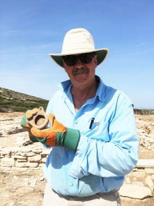 Man in a hat holding an ancient lamp he dug up.