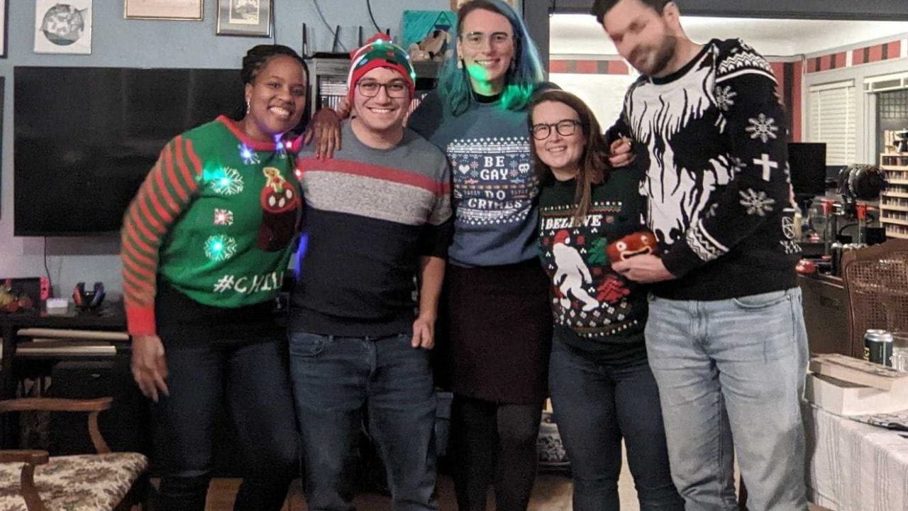 MatsuLab members and partners pose with their holiday sweaters and hat during the lab holiday party