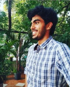 Abhi smiles in the midst of green plants.