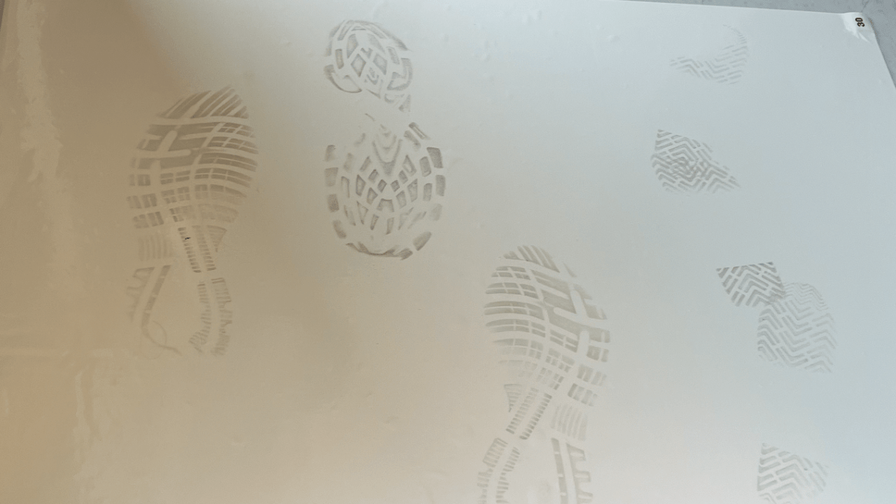 Dark grey footprints on a white sticky mat.
