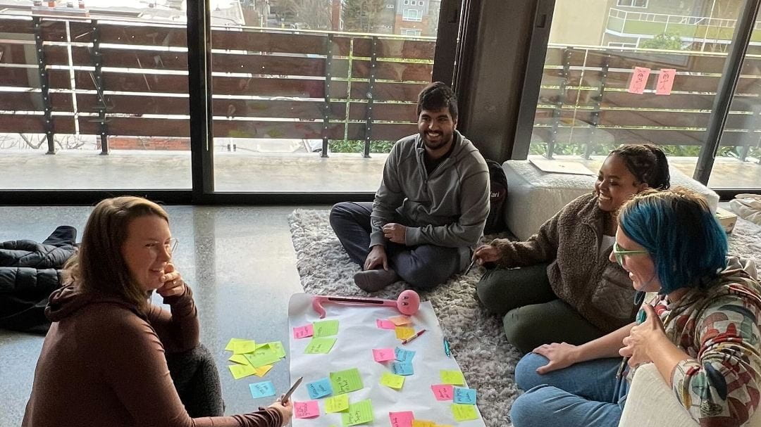 Matsulab members sitting on the floor in a brainstorming session with post its on a roll of white paper.