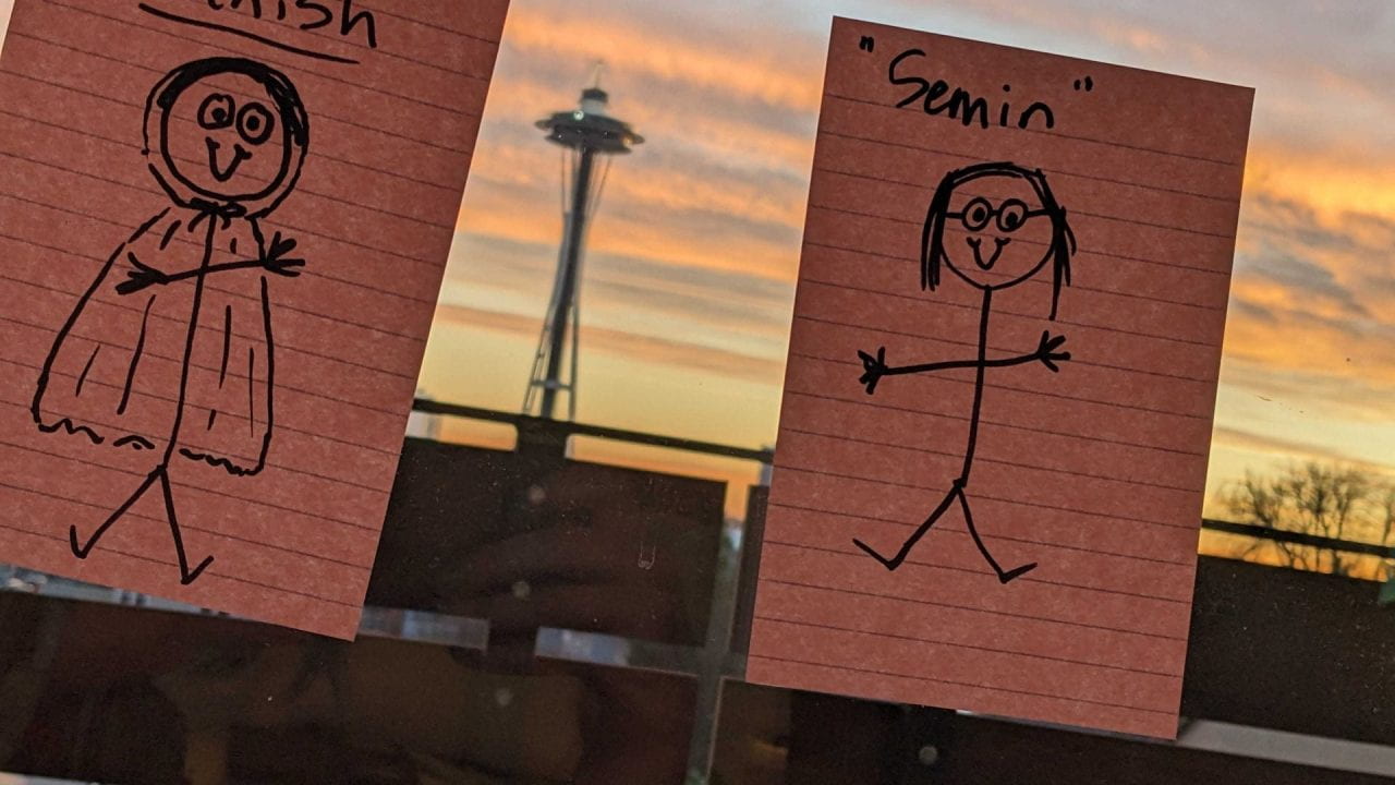 Post-its with stick figure drawings of the absent lab members, with the space needle in the background