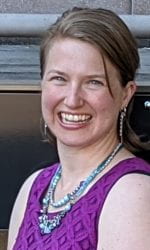 A headshot of Diana Knight posing outside Bagley Hall on the University of Washington's campus. Diana is wearing a purple dress and light blue necklace.