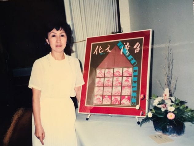 Yeen-Mei Wu in a white dress standing in front of the Taiwan Culture exhibition sign, 1986
