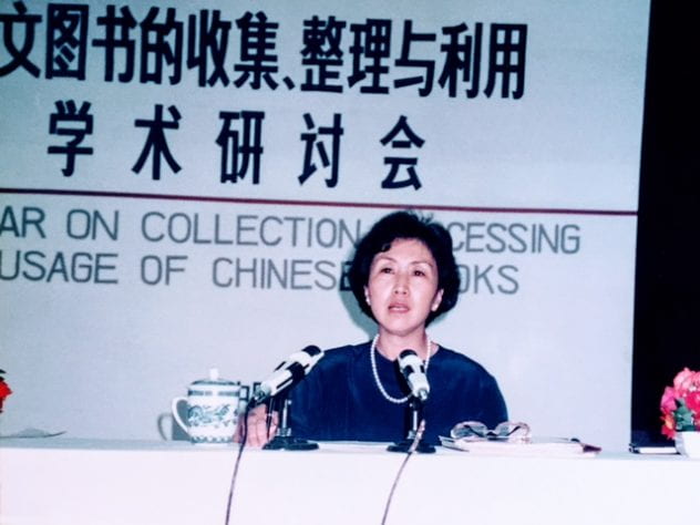 Photograph of Yeen-Mei Wu sitting behind a desk speaking at an international conference on Chinese collections, Beijing Library, August 1989