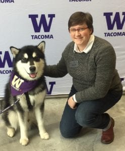 Photo of a woman with cropped hair crouched next to the UW Tacoma Mascot, Dubs II the Husky Dog!
