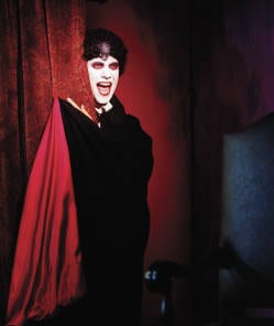 Image of a vampire appearing from behind a red velvet curtain