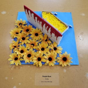 Yellow flowers, a bloody barrier, and yellow beads in a paper boat