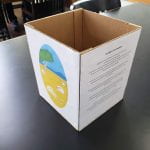 Cardboard cube with writing on one size and a graphic on another