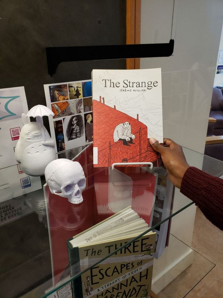 Hand reaching in to grab "The Strange" by Jérôme Ruillier