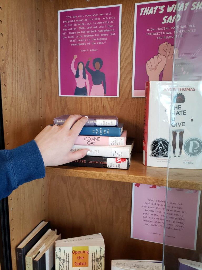 Hand reaching to grab stack of books from "That's What She Said" display