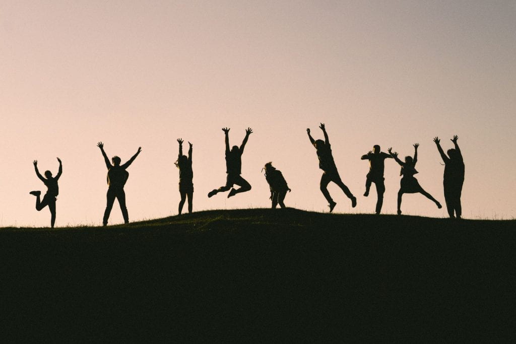 A row of people in silhouette, jumping for joy.