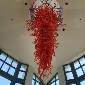 Red art glass chandelier in front of windows
