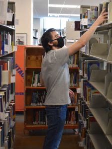 Photo of library student worker removing books from shelf