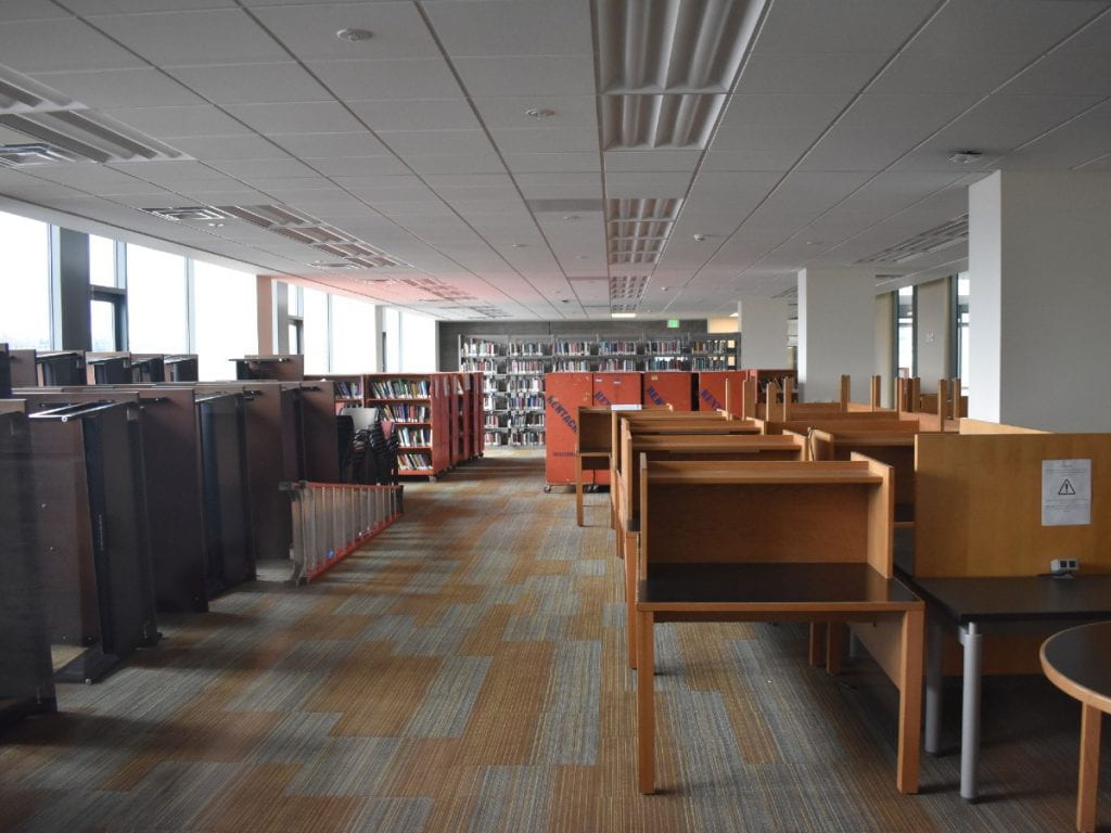 Photo of fourth floor of the Tioga Library Building on February 2, 2021, showing room with shelving, book carts, and stored furniture