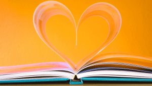 Open book with two pages folding inwards and opposite of each other to form a heart.