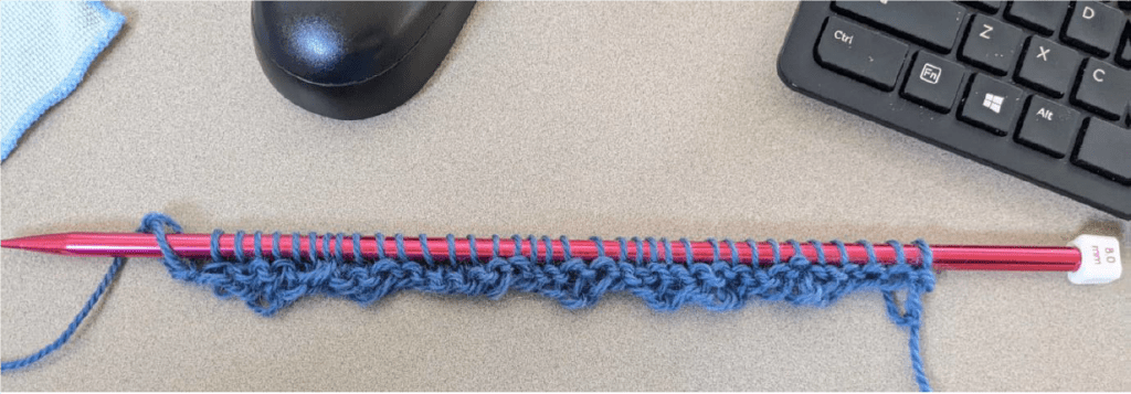 Crochet hook in front of computer setting