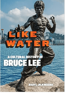 Martial artist Bruce Lee, as a statue, posed on a rock overlooking a bay. Title is Like Water, a Cultural History of Bruce Lee, by Daryl Jo Ji Maeda.