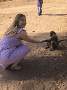 Alexis posing with a small monkey, they are shaking hands